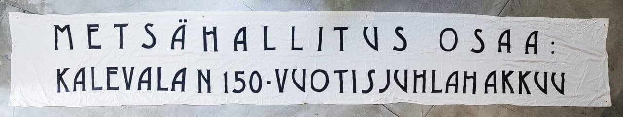 Demonstration banner: “State Forest Enterprise Celebrates 150 Years of Kalevala by Cutting the Woods”